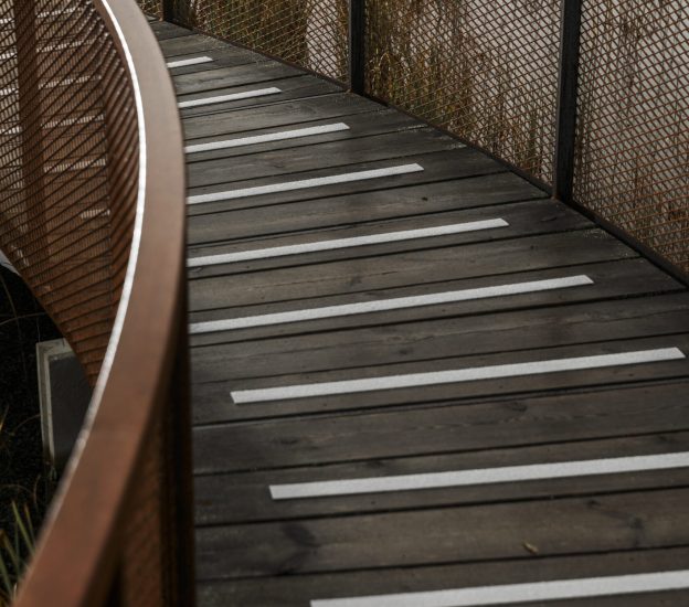 Gråa halkskyddslister på gångbro i trä
